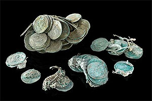 Die kupferhaltigen Silbermünzen sind durch die Korrosion zum Teil fest miteinander „verbacken“. Durch die Korrosion haben sich aber auch die Textilien erhalten, die sich auf den Münzen abzeichnen. Auffällig sind kleinere Münzstapel, die vermuten lassen, dass unterschiedliche Münzwerte in Stoff eingeschlagen gewesen sind.