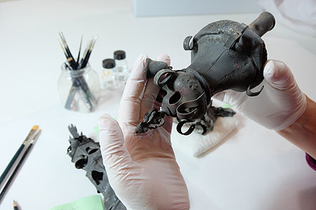 Eine Restauratorin im Museum für Franken untersucht und reinigt die Objekte sorgfältig